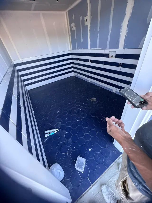 Blue bathroom floor tile with drywall and finishing work still in progress.