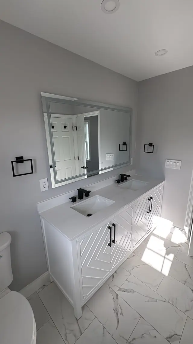 A bathroom vanity, mirror, tiled floor, and daylight from a window.