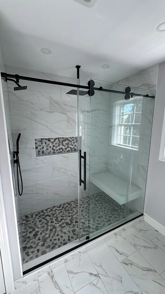 A walk-in shower with glass enclosure, wall tile, and a recessed niche.